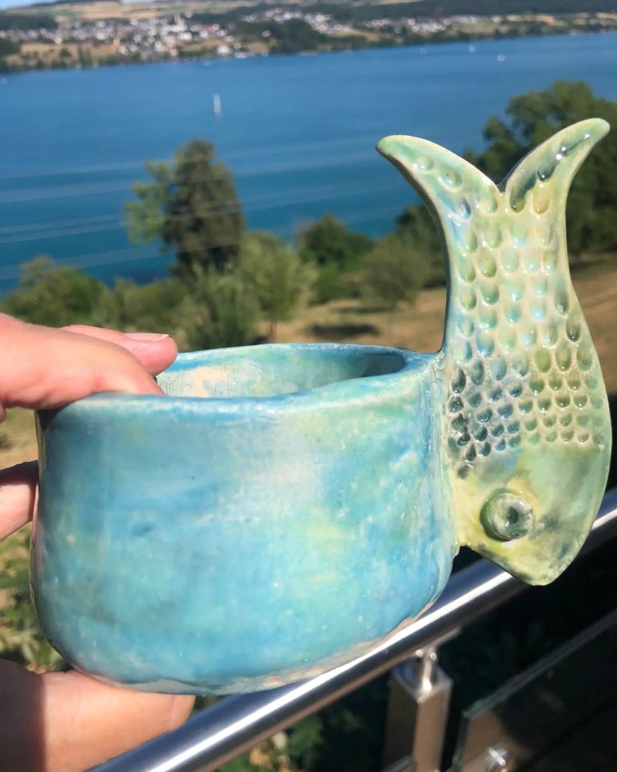 Türkis glasierte Fisch-Tasse vor dem Hallwilersee